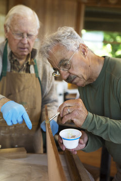 Senior shipbuilders painting boat