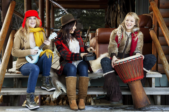 Three women playing music on porch