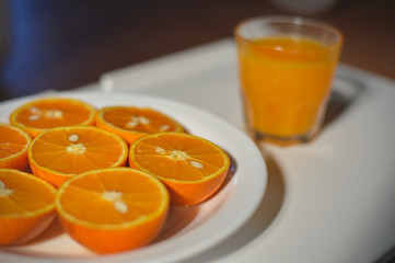 Top view closeup on fresh juice and sliced oranges on the plate.