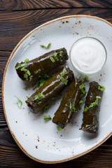 Dolmades with sour cream served on a glass plate, above view