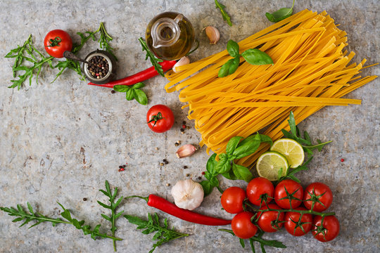 Pasta Tagliatelle and ingredients for cooking (tomatoes, garlic, basil, chili). Top view
