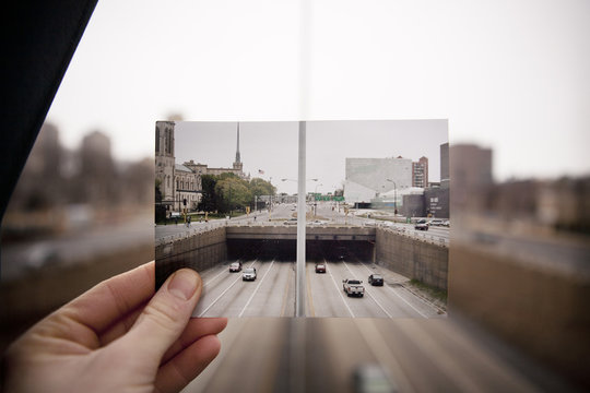 Hand holding picture of highway in front of highway