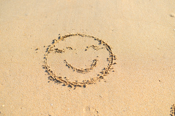Top view on happy smiley face drawing on a sand.