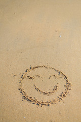 Top view on happy smiley face drawing on a sand.