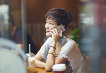 a chinese woman talking on smartphone in coffee shop