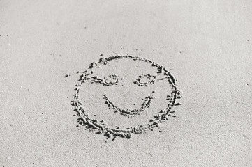 Top view on happy smiley face drawing on a sand.