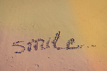 Abstract sign of word smile written, sand beach background