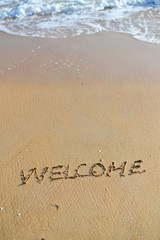 Background with welcome word sign on sandy beach outside texture