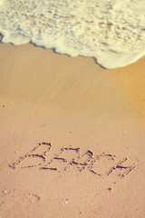 Beach sign on sandy ocean foam wave coastline