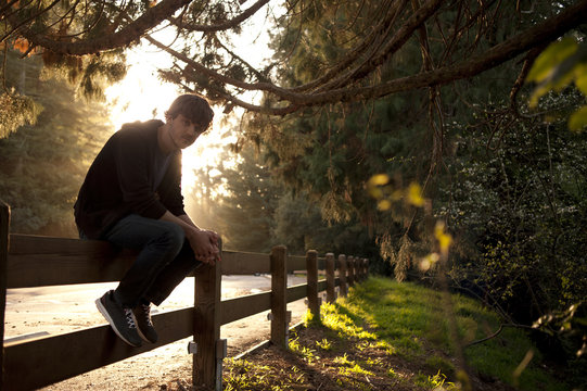 Young Man Sitting On Fence