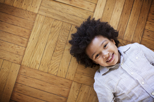 Portrait of happy boy lying on wooden floor