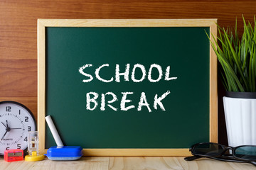 Words SCHOOL BREAK written on green chalk board on wooden table.