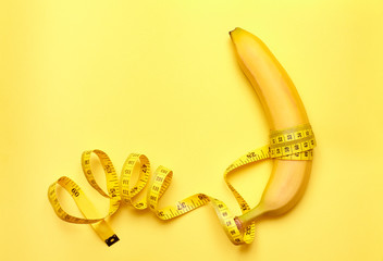Isolated banana with measuring tape on a yellow background