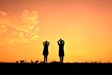 Fototapeta premium Silhouette children yoga at sky sunset