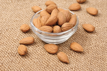 Dried almonds on glass bowl on canvas background
