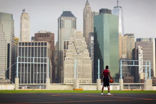Rear view of man looking at skyline while standing in basketball court 
