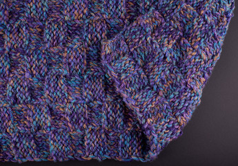 A piece of purple knitting, against a dark background 