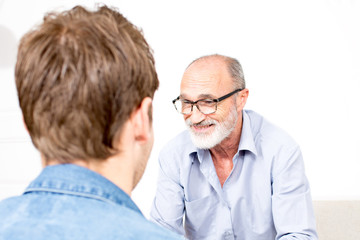Elderly man listening to a younger person smiling