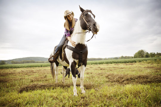 Smiling Woman Stroking Horse While Riding On Field