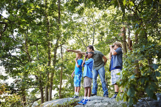 Teacher explaining students while standing on rocks in forest during field trip