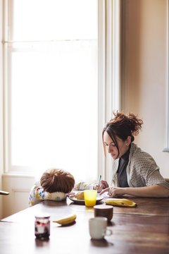 Mother assisting son while doing homework at home