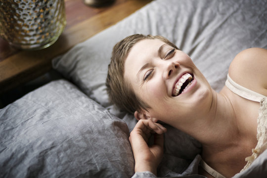 High angle view of woman laughing while lying on bed at home