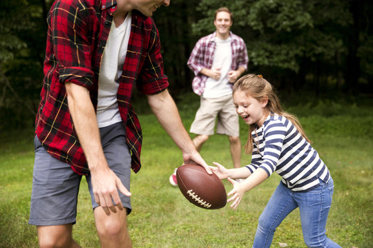 Girl playing American football with her father