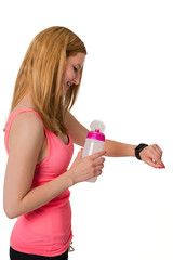 Young woman looking at digital watch with bottle in her hand