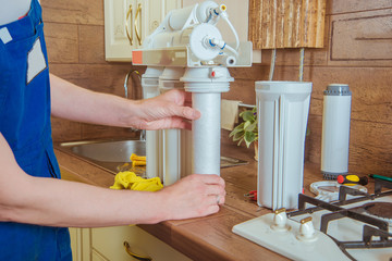 plumber installing new water filter in the kitchen