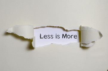 The word less is more appearing behind torn paper.