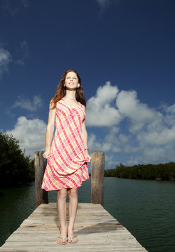 Woman standing on pier against cloudy sky