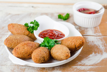 Kibbeh. Traditional Arabian meatballs with parsley in white plate on wooden background. Eastern cuisine. Selective focus