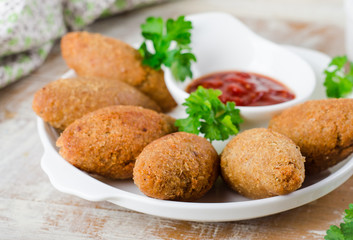 Kibbeh. Traditional Arabian meatballs with parsley in white plate on wooden background. Eastern cuisine. Selective focus