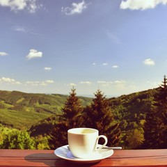 Morning cup of coffee with a beautiful mountain landscape background. Relaxation and recreation on vacation.