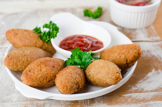 Kibbeh. Traditional Arabian meatballs with parsley in white plate on wooden background. Eastern cuisine. Selective focus