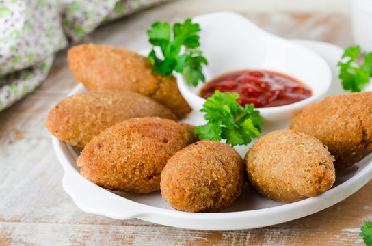 Kibbeh. Traditional Arabian meatballs with parsley in white plate on wooden background. Eastern cuisine. Selective focus