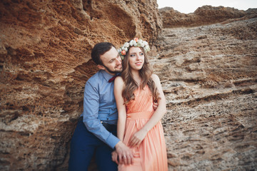 Romantic loving couple walking on the beach with rocks and stones