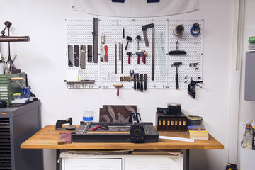 Letterpress on table and tools hanging on wall in workshop