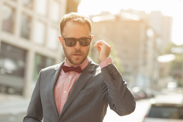 Stylish businessman in sunglasses walking at city downtown