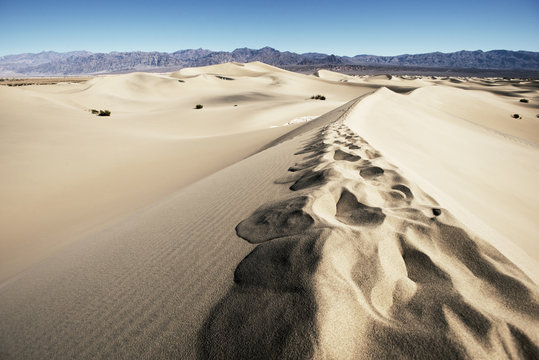 Scenic view of sand by mountains against clear blue sky