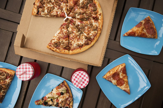 Overhead view of pizza with blue plates and drinks on wooden table