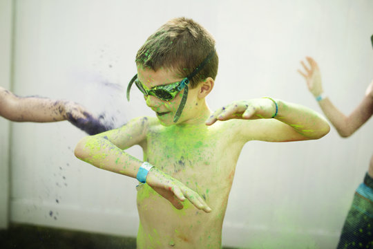 Boy wearing swimming goggles playing with color powder
