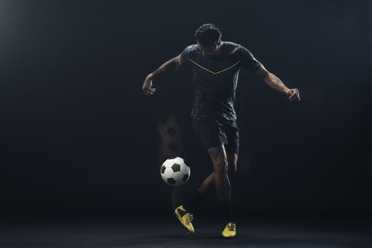 Young athlete playing soccer against black background
