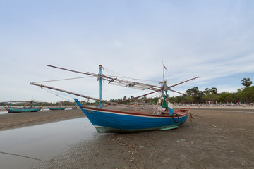 Naklejka na ściany i meble Wooden fishing boat on the low tide beach.