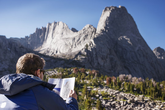 Rear view of hiker reading map against mountain