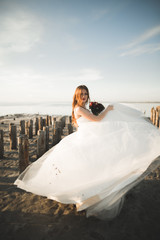 Fototapeta na wymiar Beautiful young bride with bridal bouquet posing on the background sea