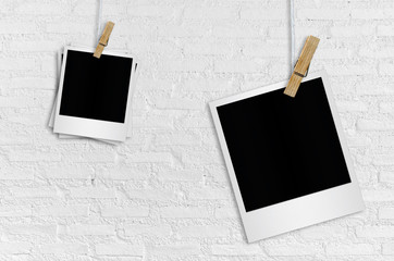 Blank polaroid photo papers on white brick wall background.