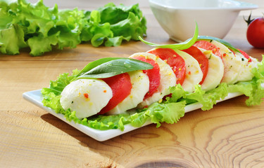 Caprese salad on white plate over wooden table