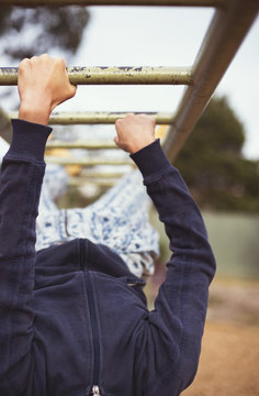 Mid section of young woman hanging on monkey bars