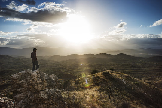 Hiker Standing On Rock By Mountains Against Sky On Sunny Day